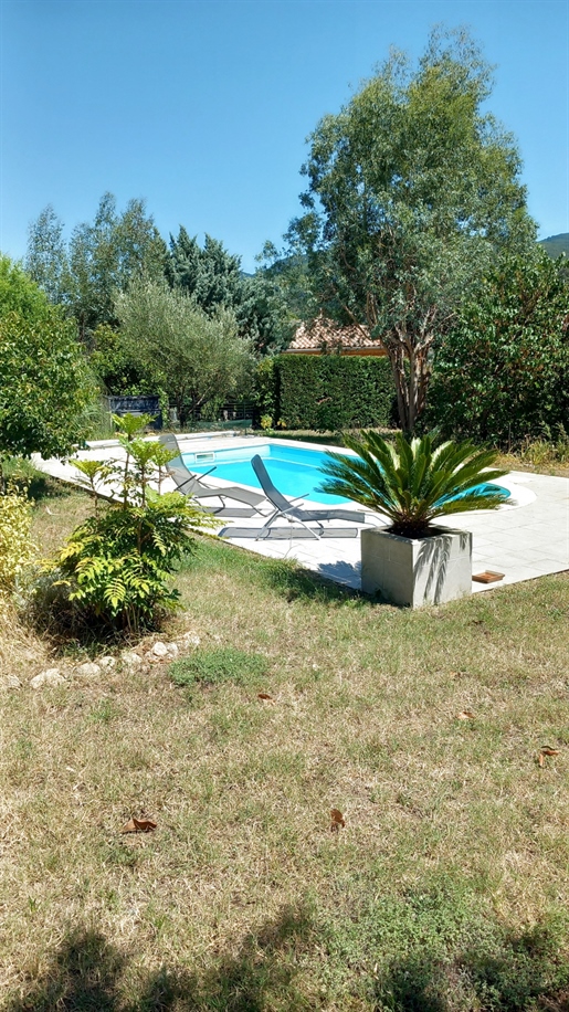 Einstöckige Villa mit großer Garage und Swimmingpool im bewaldeten Garten.