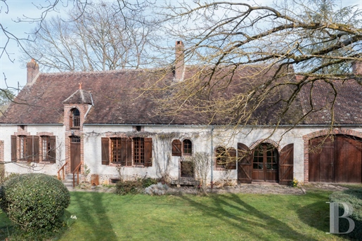 An elegant 18th-century village house with stone outbuildings and tree-dotted grounds in Burgundy, 1