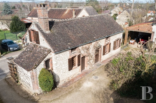 An elegant 18th-century village house with stone outbuildings and tree-dotted grounds in Burgundy, 1