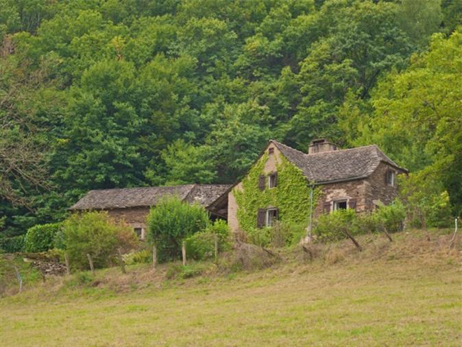 Kamenný dům, stodoly a pole s výhledem do údolí vynikající v Aveyron.